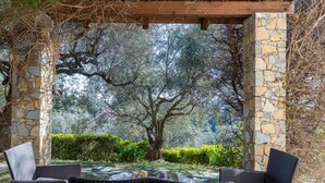 Une pergola en pierre avec des meubles en osier, sous un ciel dégagé.