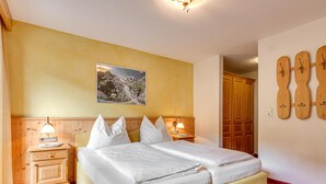 Une chambre d’hôtel avec un lit double, deux tables de chevet avec des lampes, une armoire en bois et une décoration murale représentant une guitare.