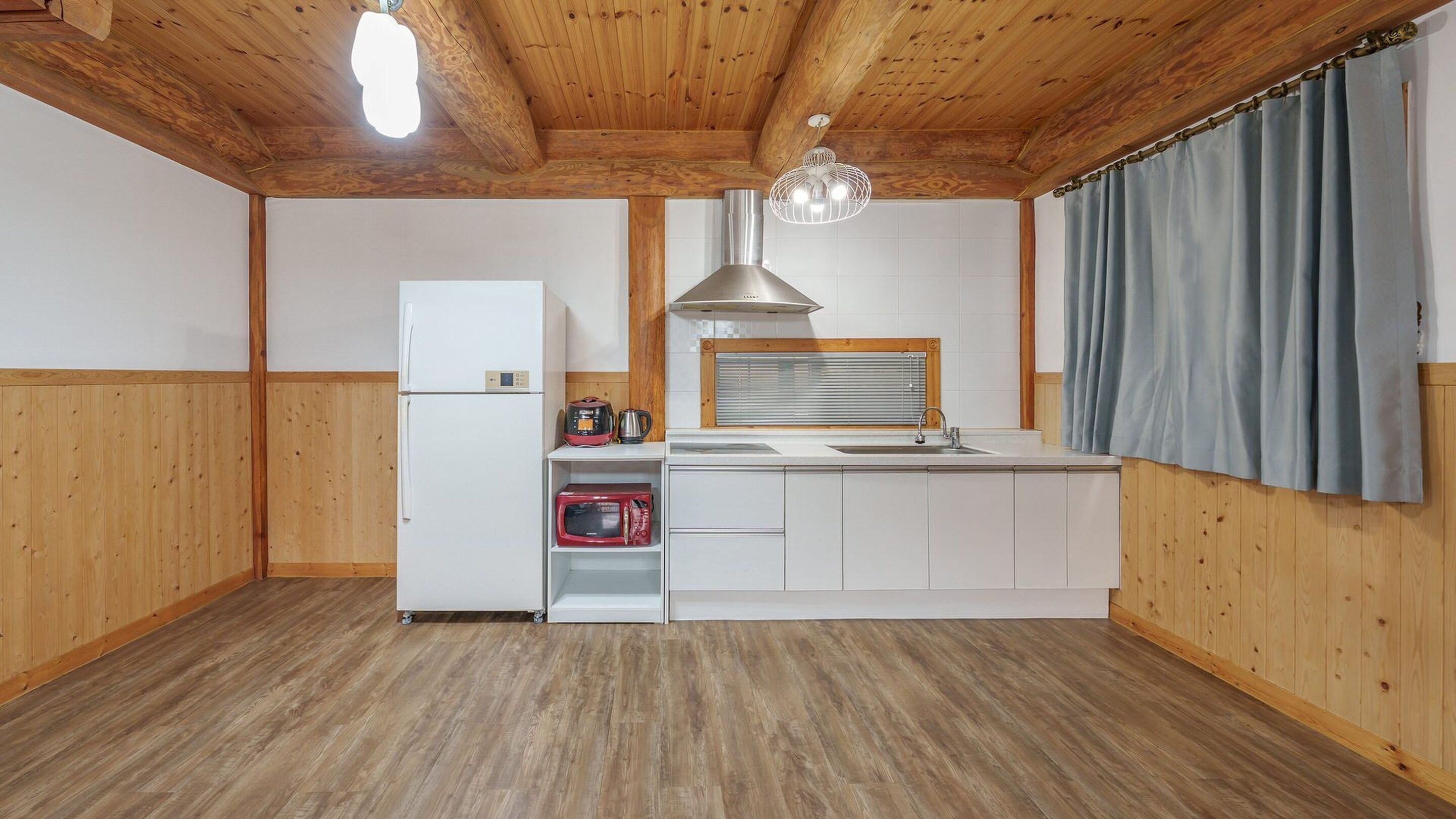 Een praktische keuken met een koelkast, magnetron, waterkoker en een spoelbak.