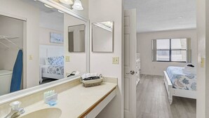 A bathroom with a large mirror, a sink, and a towel rack.