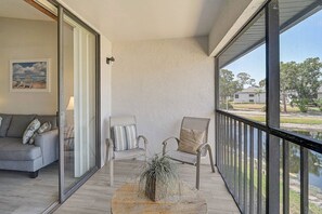 Enjoy the view from this balcony with a sofa, two chairs, and a potted plant.