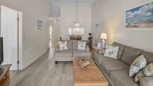 A living room with a grey sofa, a wooden coffee table, and a dining area with a table and chairs.