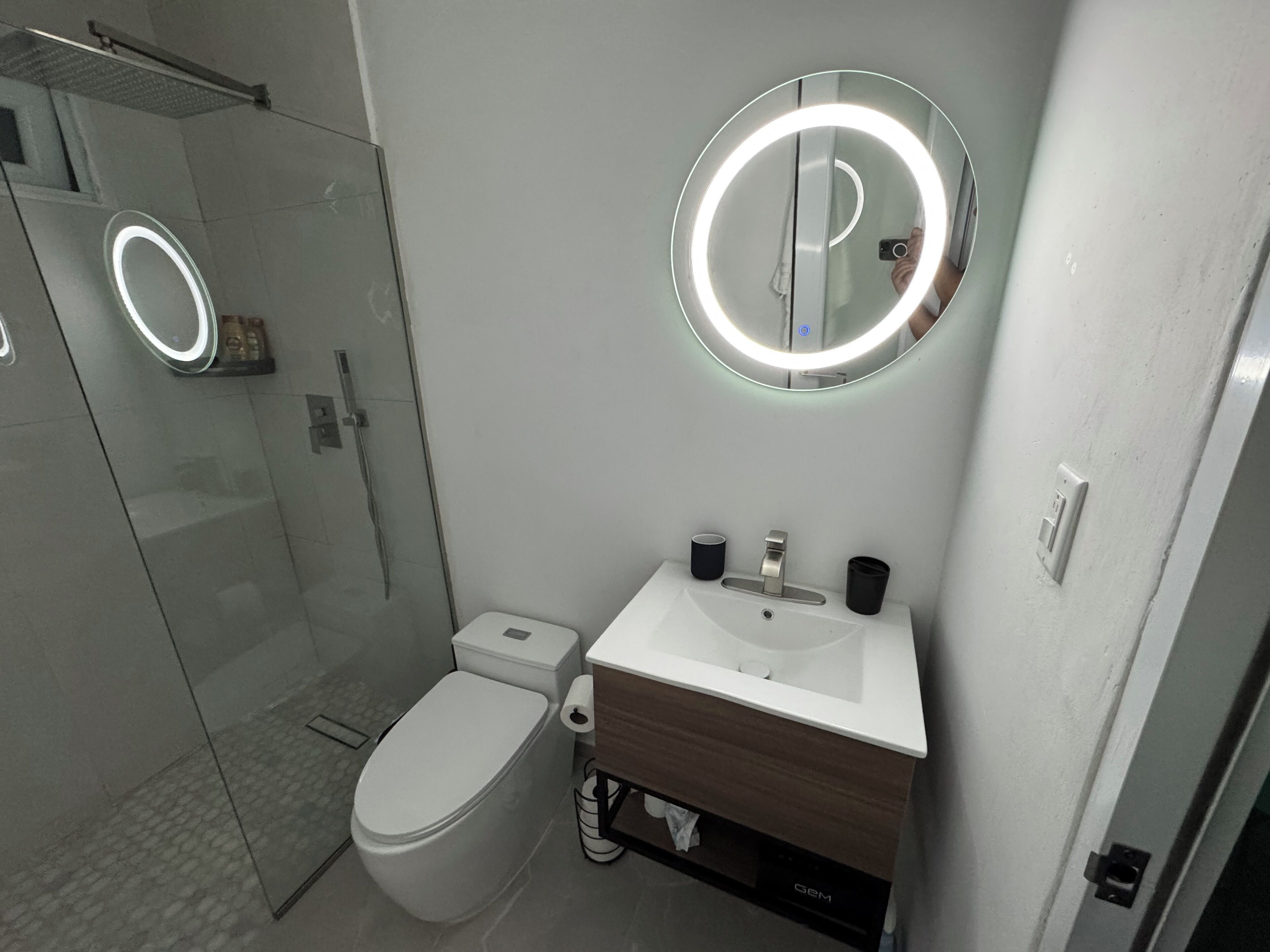 A modern bathroom with a toilet, sink, and mirror.