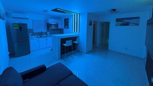 A modern kitchen with a central island, a dining area with bar stools, and a living room with a sofa. - Villa Tropicana  (Carolina)