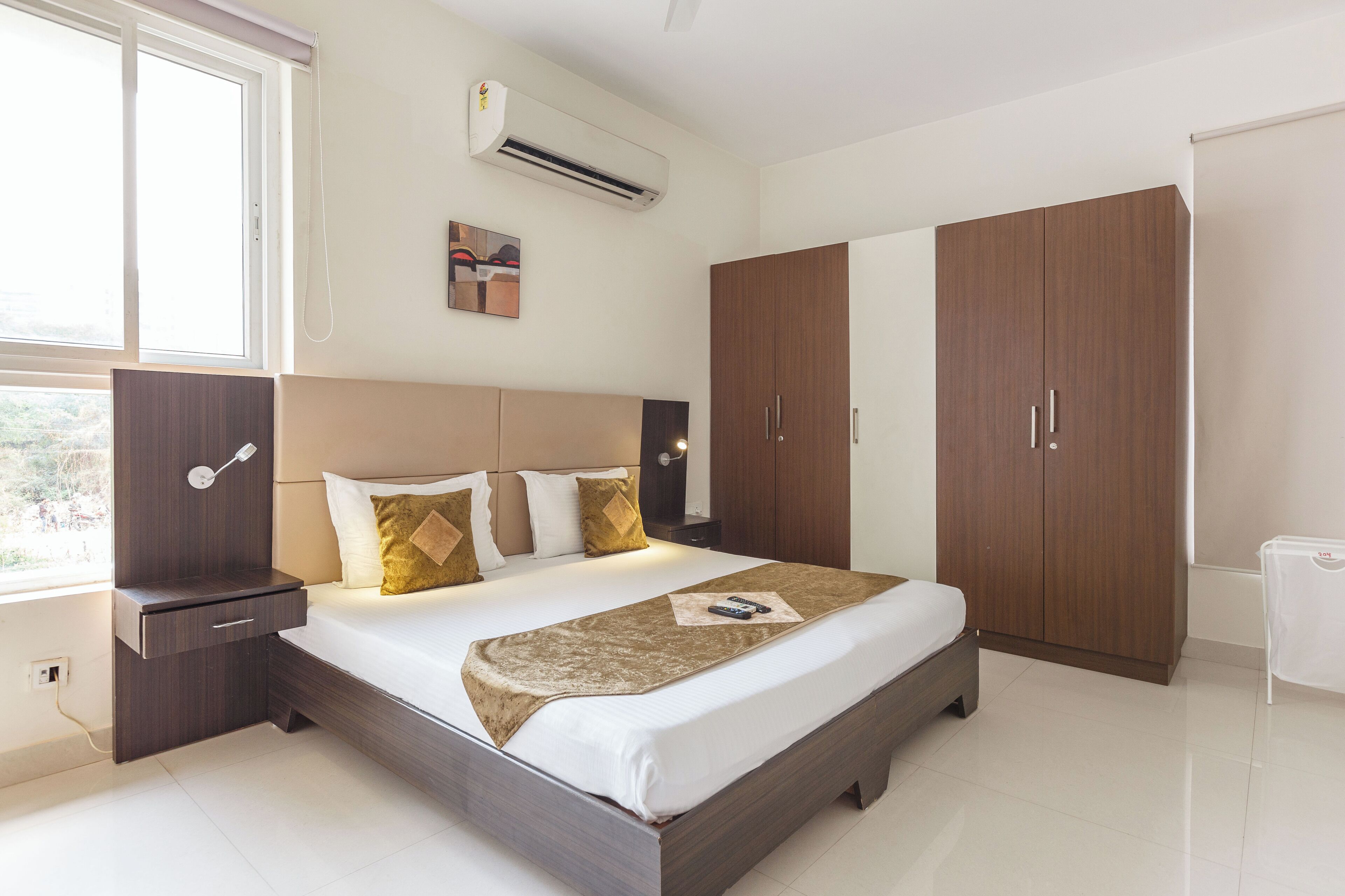 Une chambre moderne avec un grand lit, une armoire, une table de chevet et un appareil de climatisation.