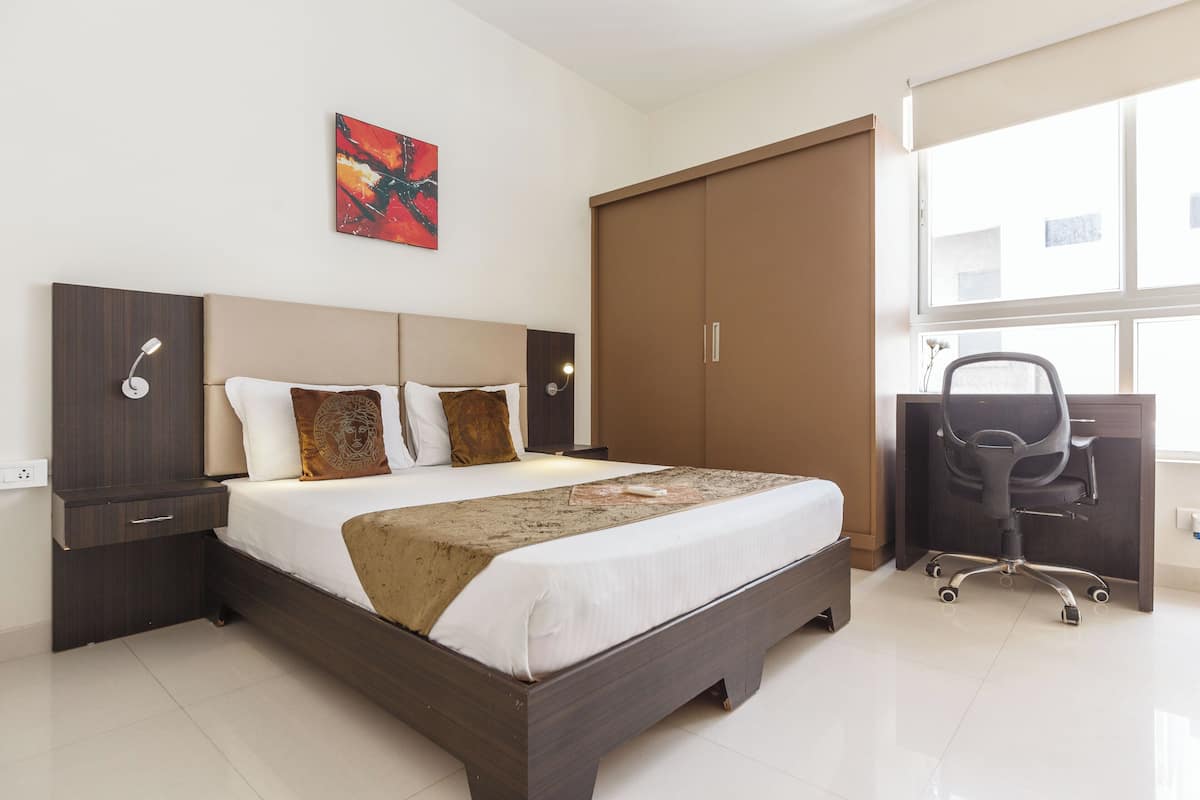 Una habitación de hotel con una cama grande, un escritorio, una silla y un armario.