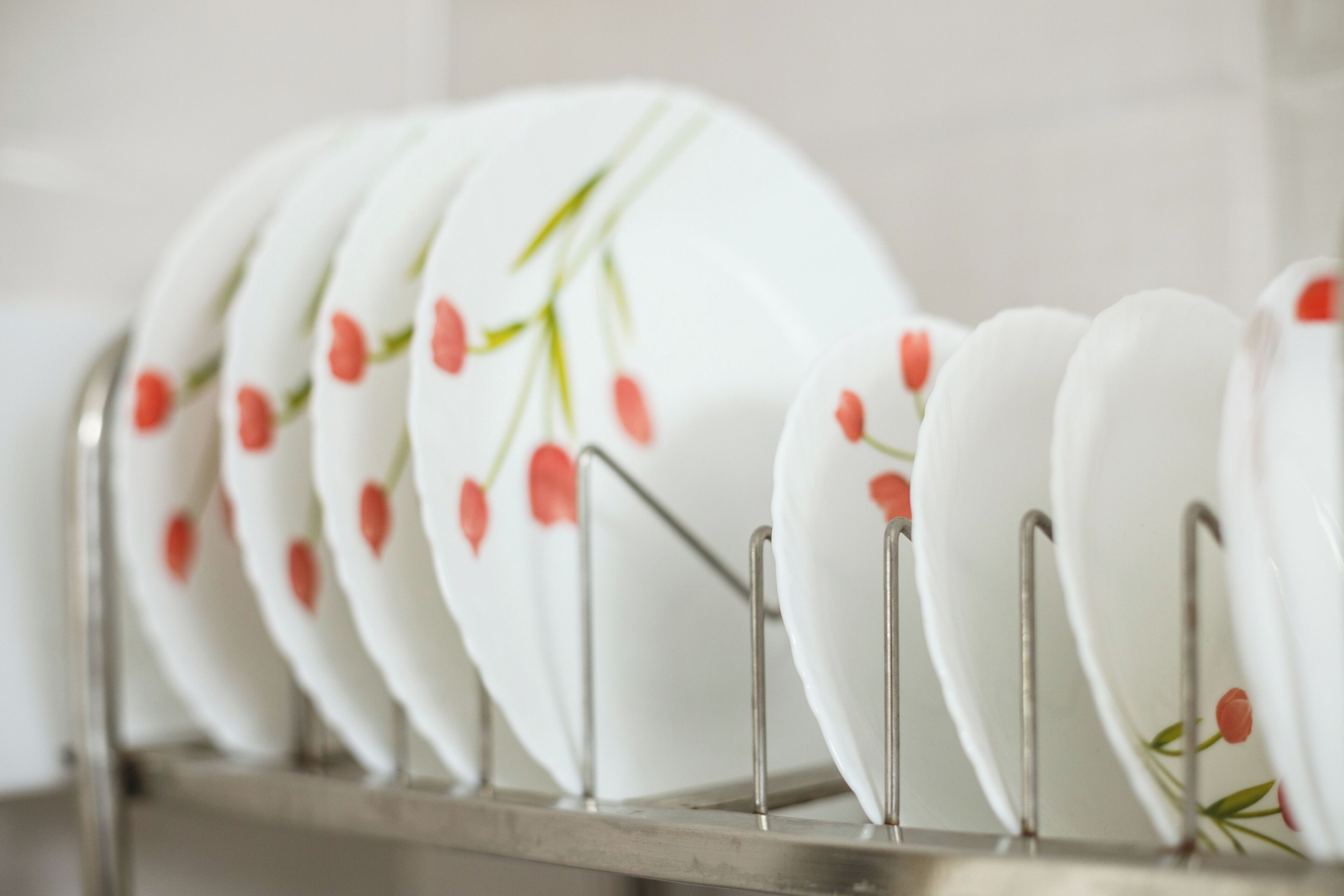 A rack of white plates with red tulip designs.