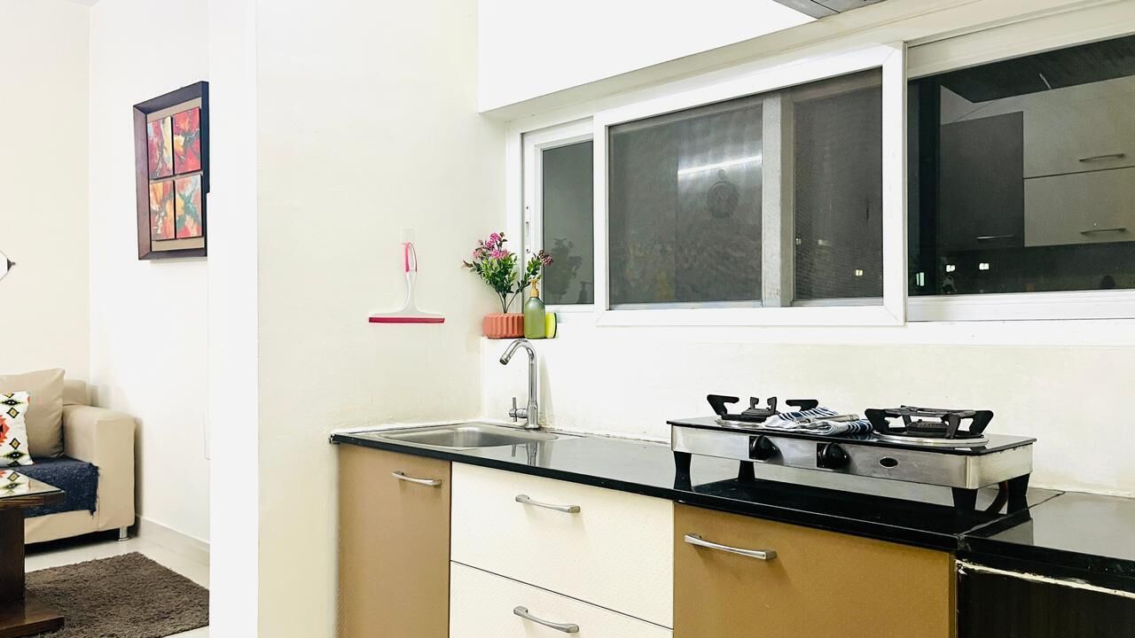 Eine kleine Küche mit Gaskochfeld, Spüle und einem Fenster über der Arbeitsplatte.