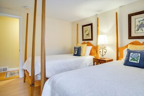 Una camera d'albergo con due letti, un comodino, una lampada e un quadro appeso al muro.