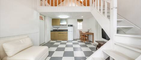 A compact living space with a kitchenette, a dining area, and a staircase leading to an upper level.