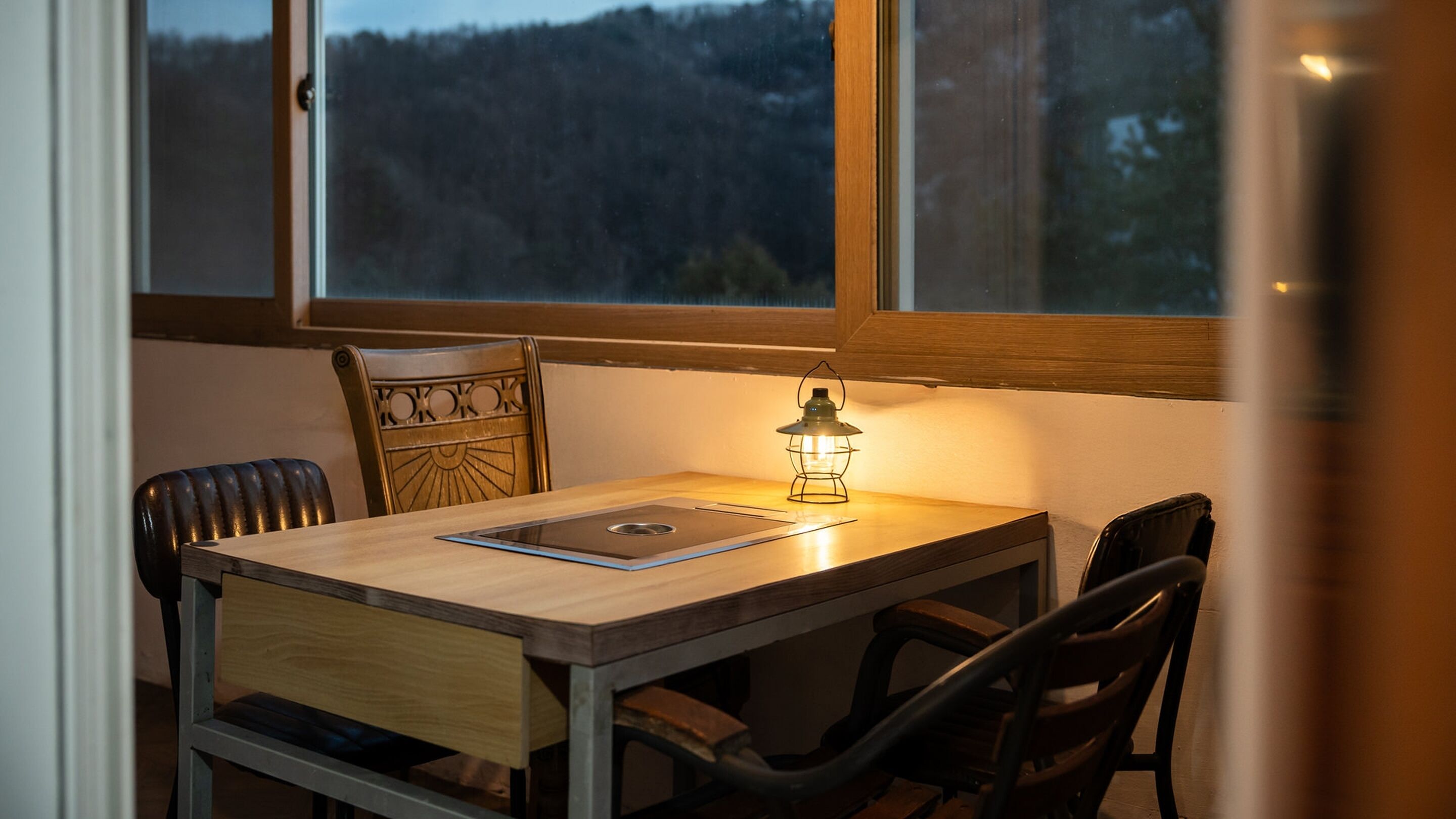 A small dining table with a metal tray, a wooden chair, and a table lamp.