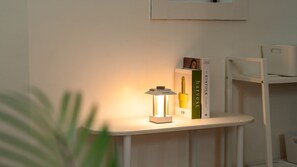 Une étagère blanche sur laquelle se trouve une lanterne blanche, un livre vert intitulé « Le guide Kinfolk pour une vie durable » et un livre blanc de Nathan Williams.