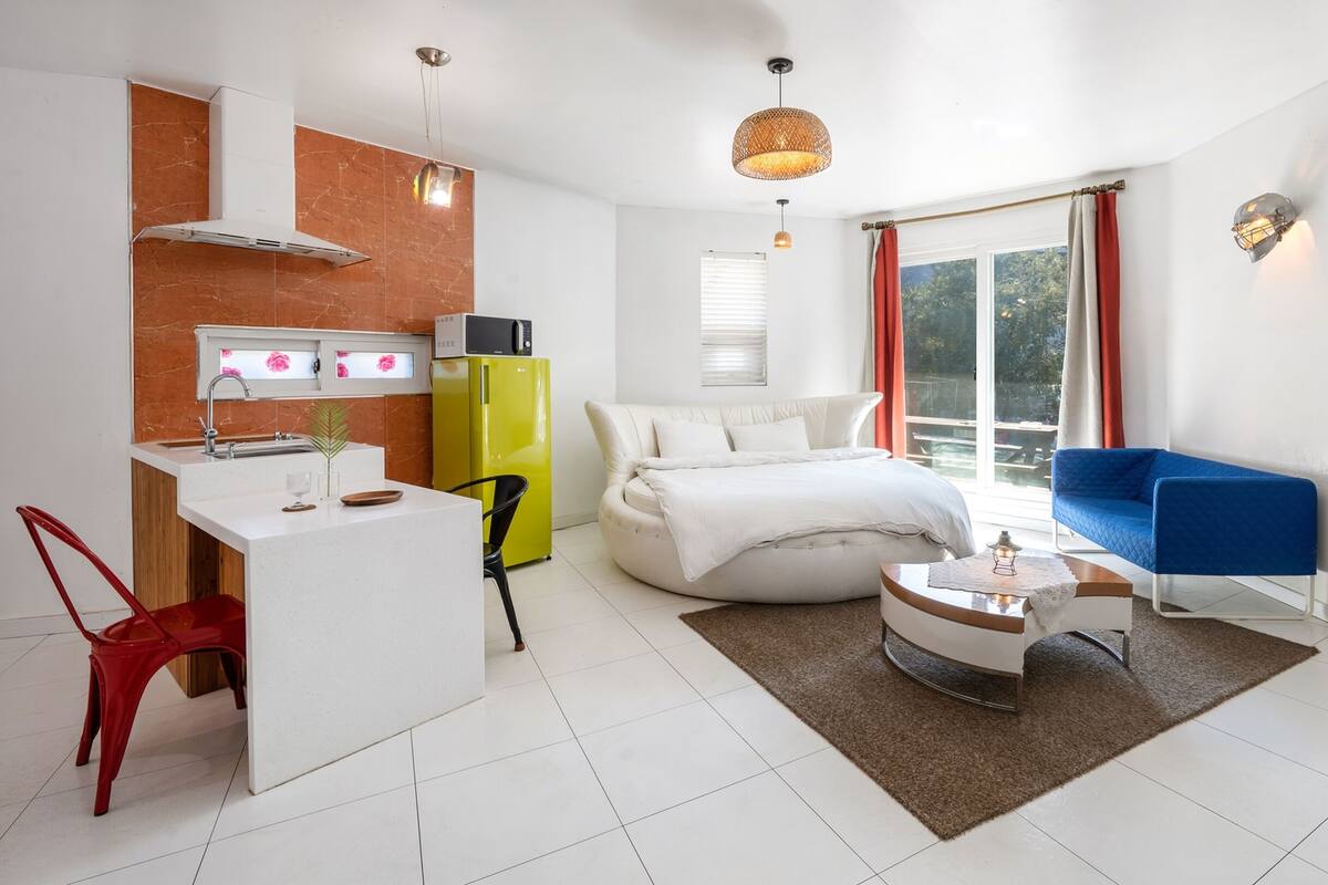 Ein modernes, helles Zimmer mit Bett, Sofa, Essbereich und Küche.