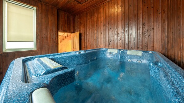Un bain à remous dans une pièce en bois, avec une fenêtre et une porte.