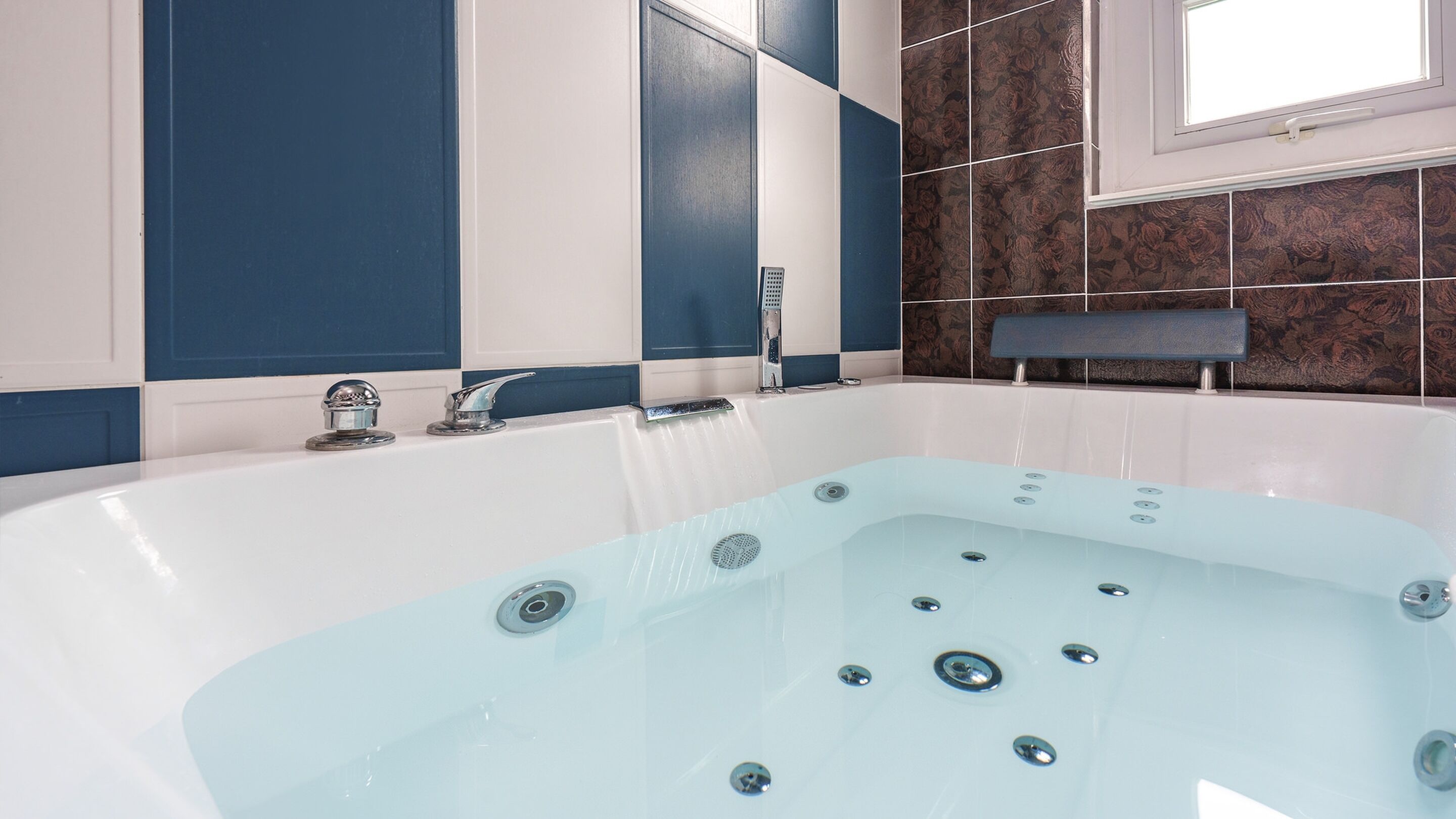 A modern bathroom with a freestanding bathtub, a handheld showerhead, and a window providing natural light.