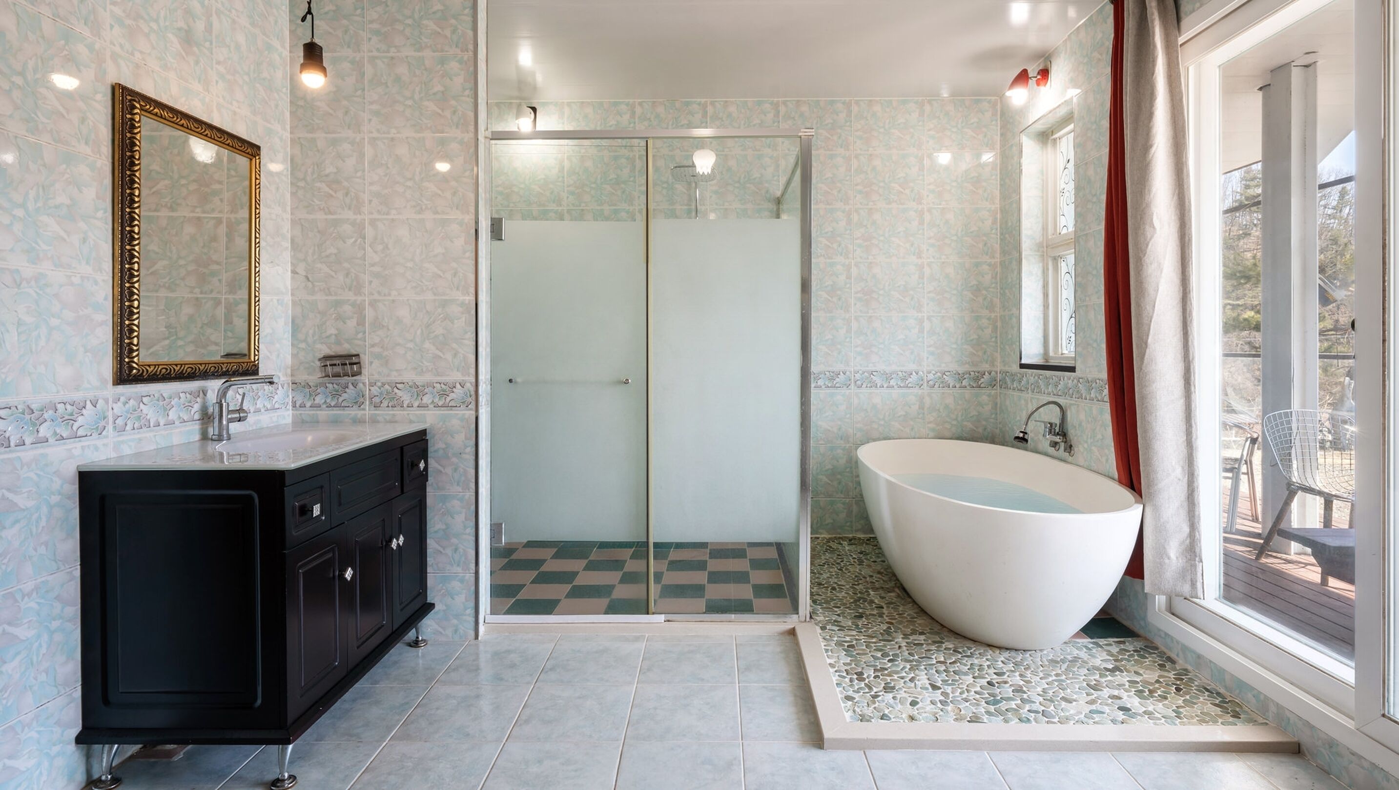 Un baño moderno con una bañera independiente, ducha con mampara de cristal y un espejo grande.
