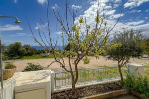 A tree-lined outdoor area with a metal fence, a concrete wall, and a metal lamp post.