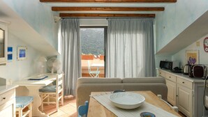 Una habitación con una mesa de comedor, un sofá, un televisor y una ventana con cortinas.