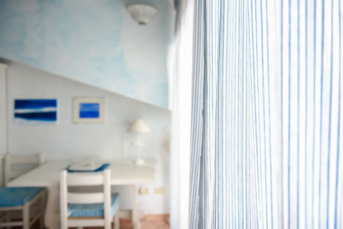 A room with a bed, a desk, and a chair. There are two framed pictures on the wall.