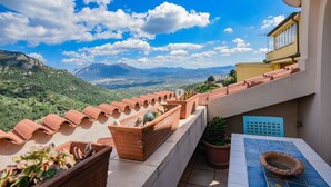 Una terraza con macetas de terracota, una mesa de baldosas y vistas a las montañas.