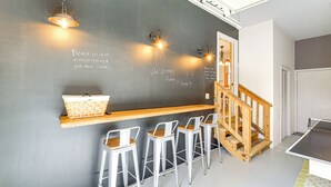 Eine Bar mit einer Tafelwand, einer Holztresen, Metallhockern und einem Tischtennisch.