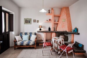 Ein Wohnzimmer mit Sofa, einem kleinen Tisch, einem Sessel, einem Kamin und einem Regal mit Dekoration.