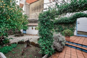 Ein Innenhof mit Garten, einem kleinen Wasserspiel und einem Pflasterweg.