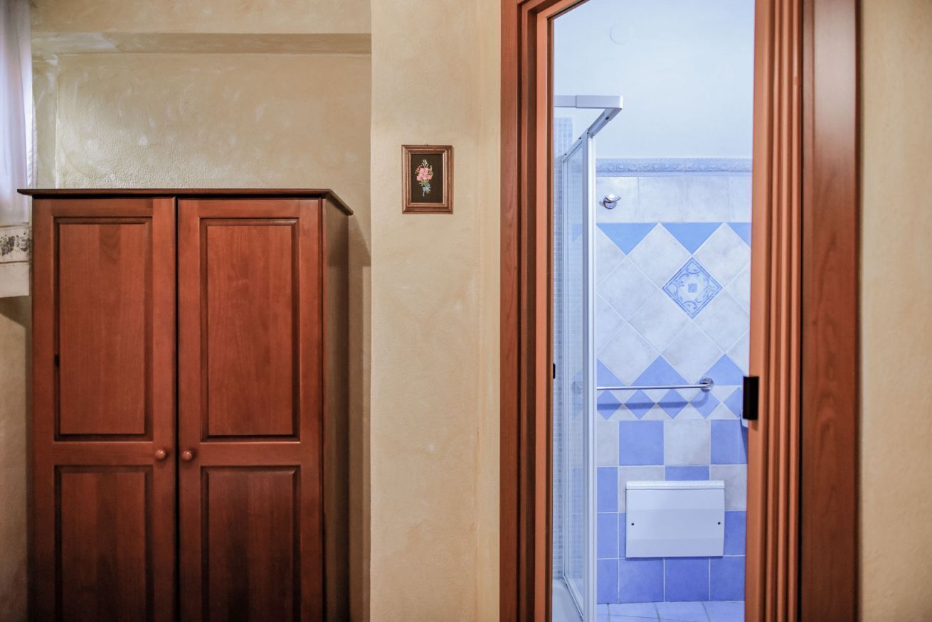 Ein Badezimmer mit Holzschrank, einem gerahmten Bild an der Wand und einer Duschkabine mit blauen Fliesen.