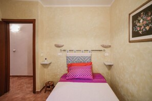 Ein Schlafzimmer mit einem Bett, einem Kopfteil, einem Nachttisch, einem Wandregal und einer Tür.