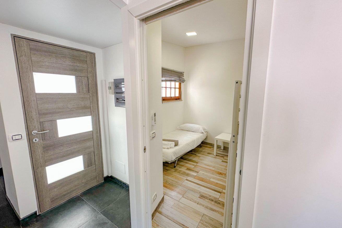 Una habitación con cama, una mesita y una ventana con persianas.