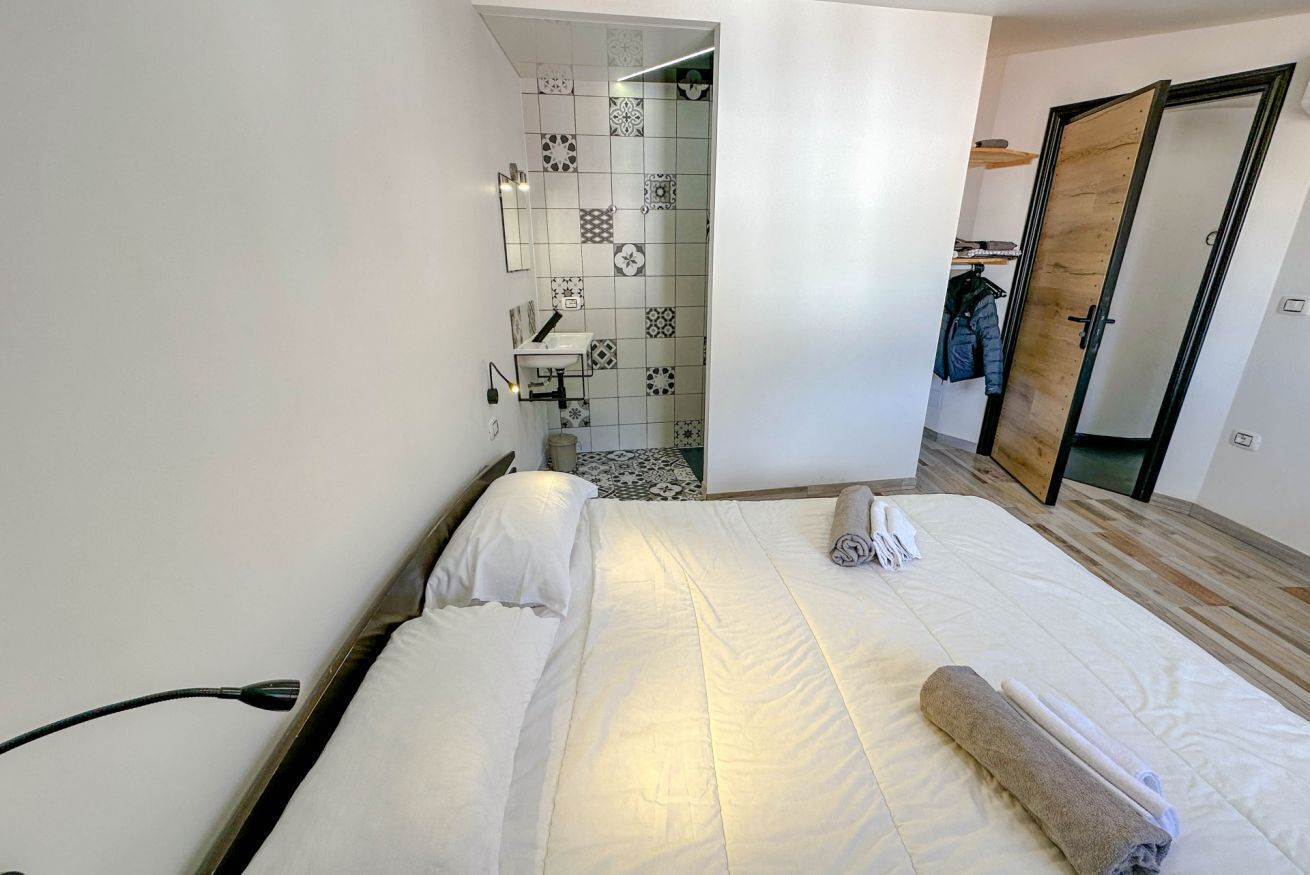 Een hotelkamer met een bed, een badkamer met wastafel en spiegel, en een kledingkast.
