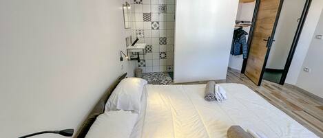 Een hotelkamer met een bed, een badkamer met wastafel en spiegel, en een kledingkast.
