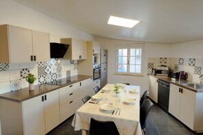 Eine moderne Küche mit Esstisch für vier Personen, eingebautem Backofen und Fenster mit Blick.