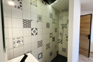 Casa de banho com azulejos estampados, uma pia branca e uma porta de madeira.