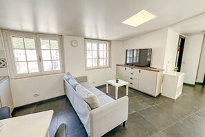 Ein modernes Wohnzimmer mit einer Couch, einem Fernseher und einem kleinen Tisch mit einer Pflanze.