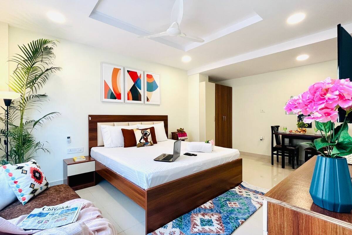 Una habitación de hotel moderna con cama, mesita de noche, lámpara y escritorio con silla.