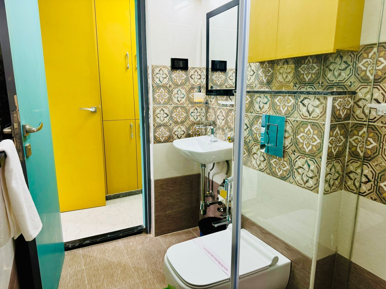 A bathroom with a yellow door, a white sink, and patterned tiles.