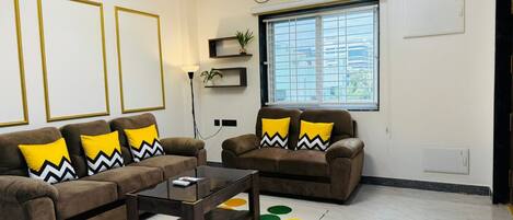 Ein Wohnzimmer mit zwei braunen Sofas, einem Glastisch und einem Teppich mit Muster.