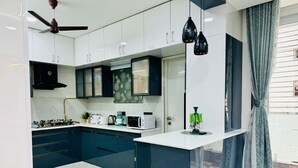 Una cocina moderna con armarios blancos, una estufa negra y una ventana con cortinas grises.