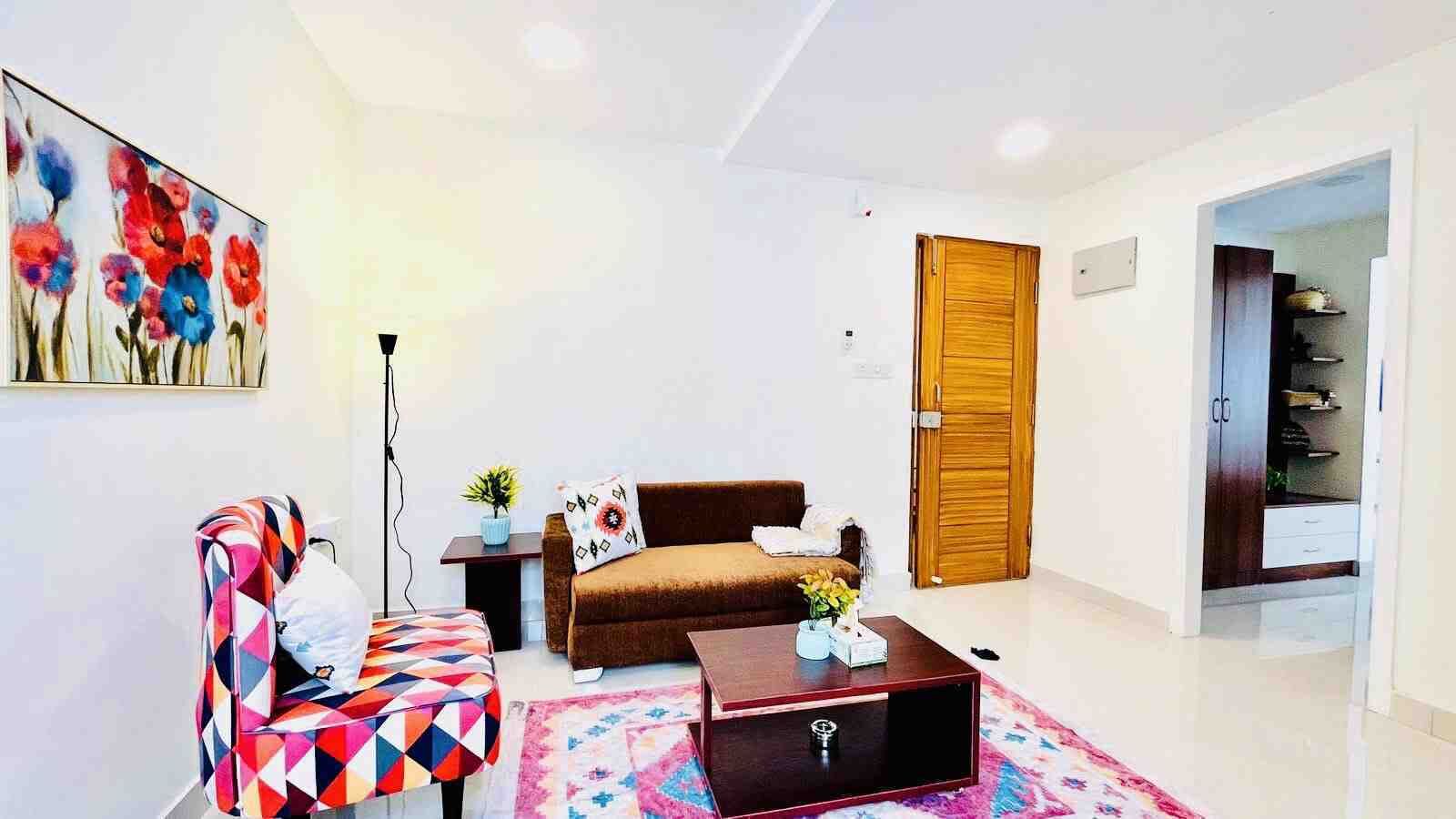 Una sala de estar moderna con un sofá, un sillón colorido, una mesa de centro y un cuadro en la pared.