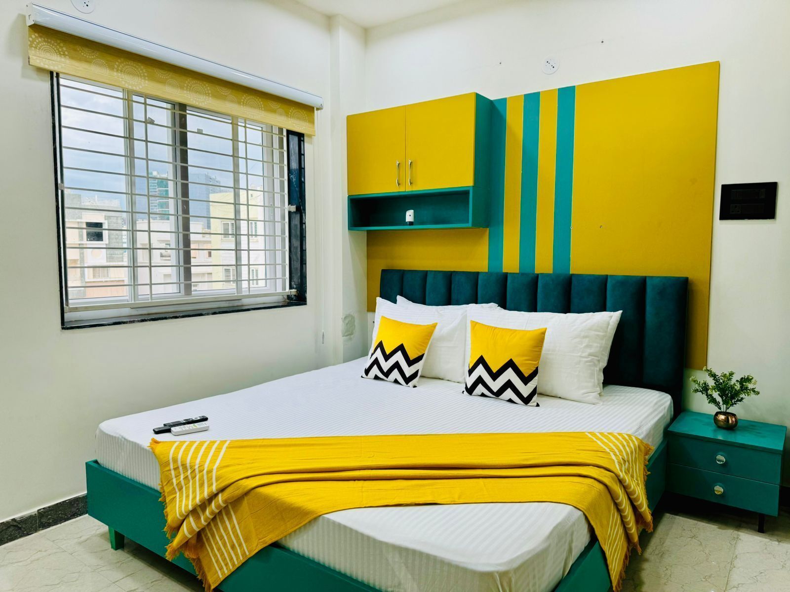 A bedroom with a bed, a nightstand, a window, and a wall unit.