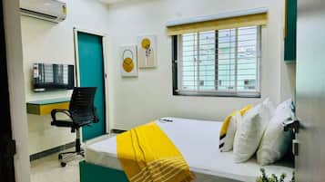 A bedroom with a bed, a desk, and a chair.