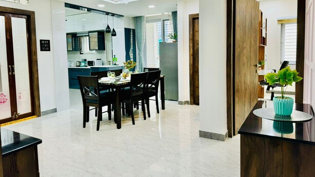 Una cocina moderna con armarios blancos, un comedor con una mesa de mármol y una araña.