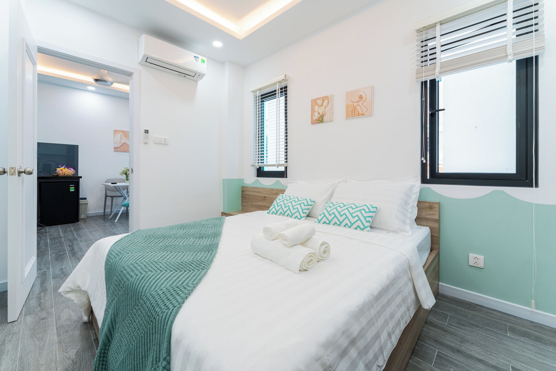 Una habitación de hotel moderna con cama, escritorio y una kitchenette pequeña.