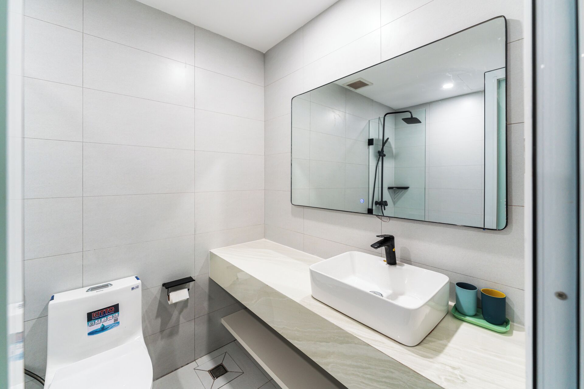 Une salle de bain moderne avec un lavabo blanc, un grand miroir et une douche.