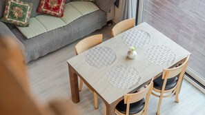 A dining area with a table and chairs, a sofa with cushions, and a window with curtains. - Yangyang Sunrise and Sunset Private Pens (Yangyang)