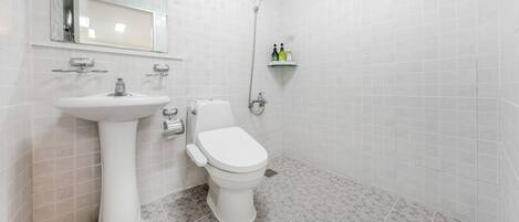 A bathroom with a white sink, toilet, and shower.