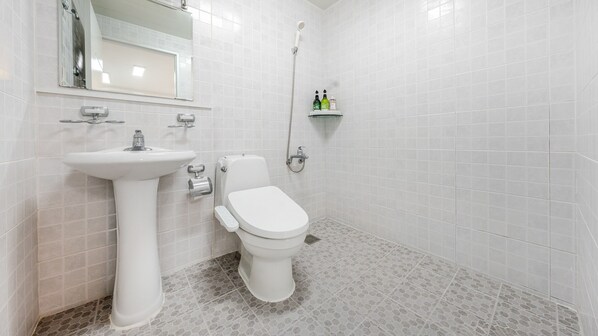 Un baño con lavamanos, inodoro y ducha blancos.
