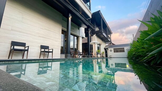 A modern building with a glass pool, outdoor seating, and a balcony. - Sareeviengping Hotel Chiangmai  (Mae Rim)