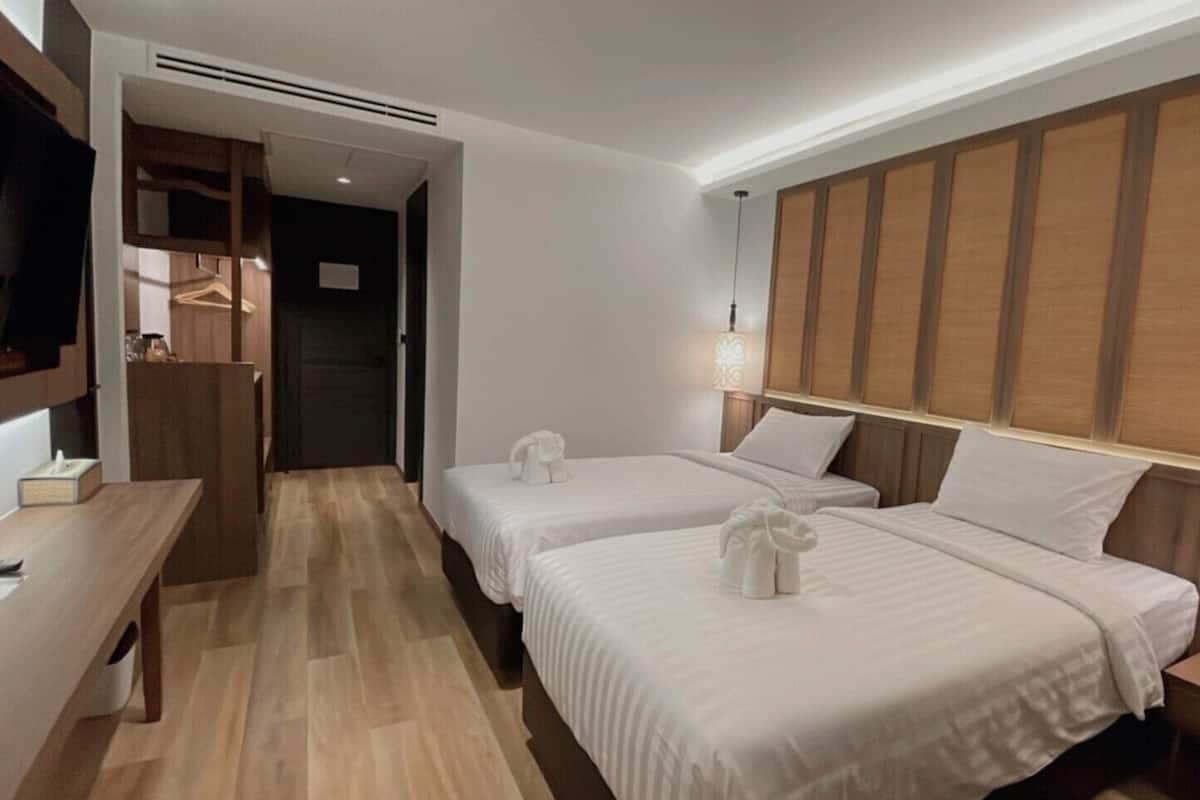A hotel room with two beds, a desk, and a TV.